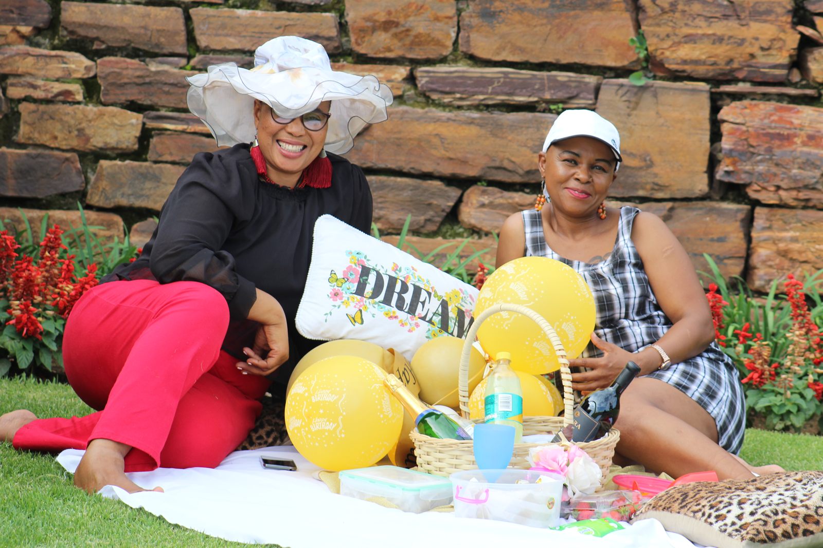 Two women at an outdoor picnic with yellow balloons