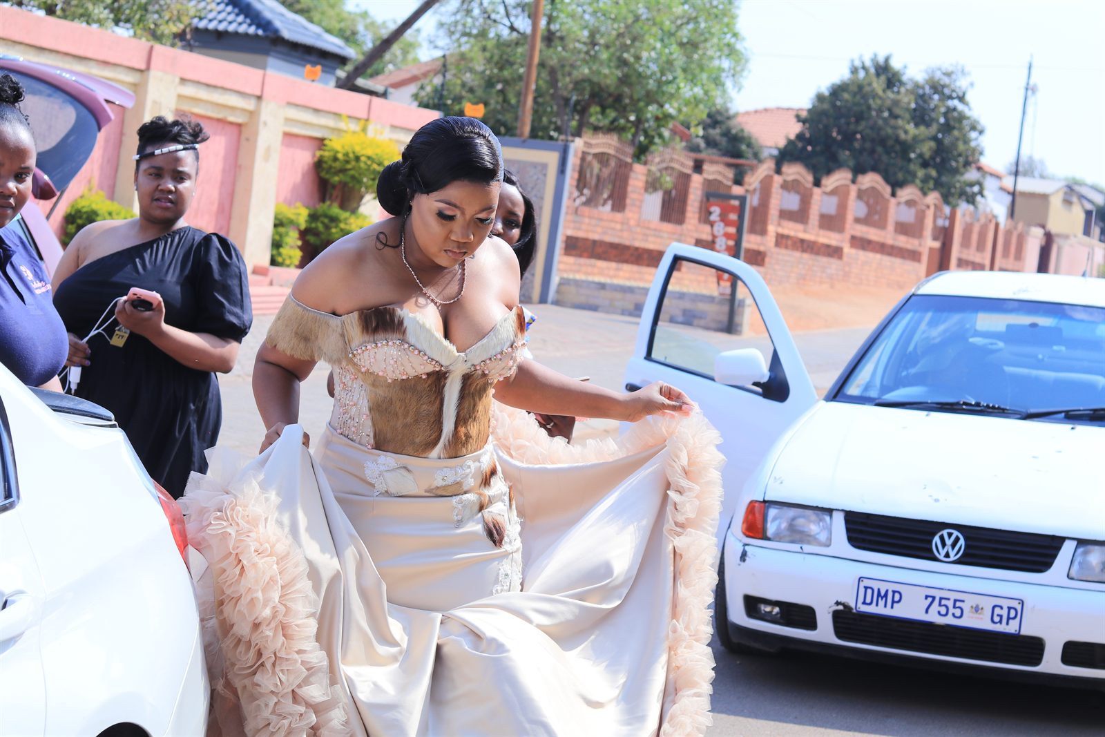 A woman in traditional dress photographed outdoors beside parked cars